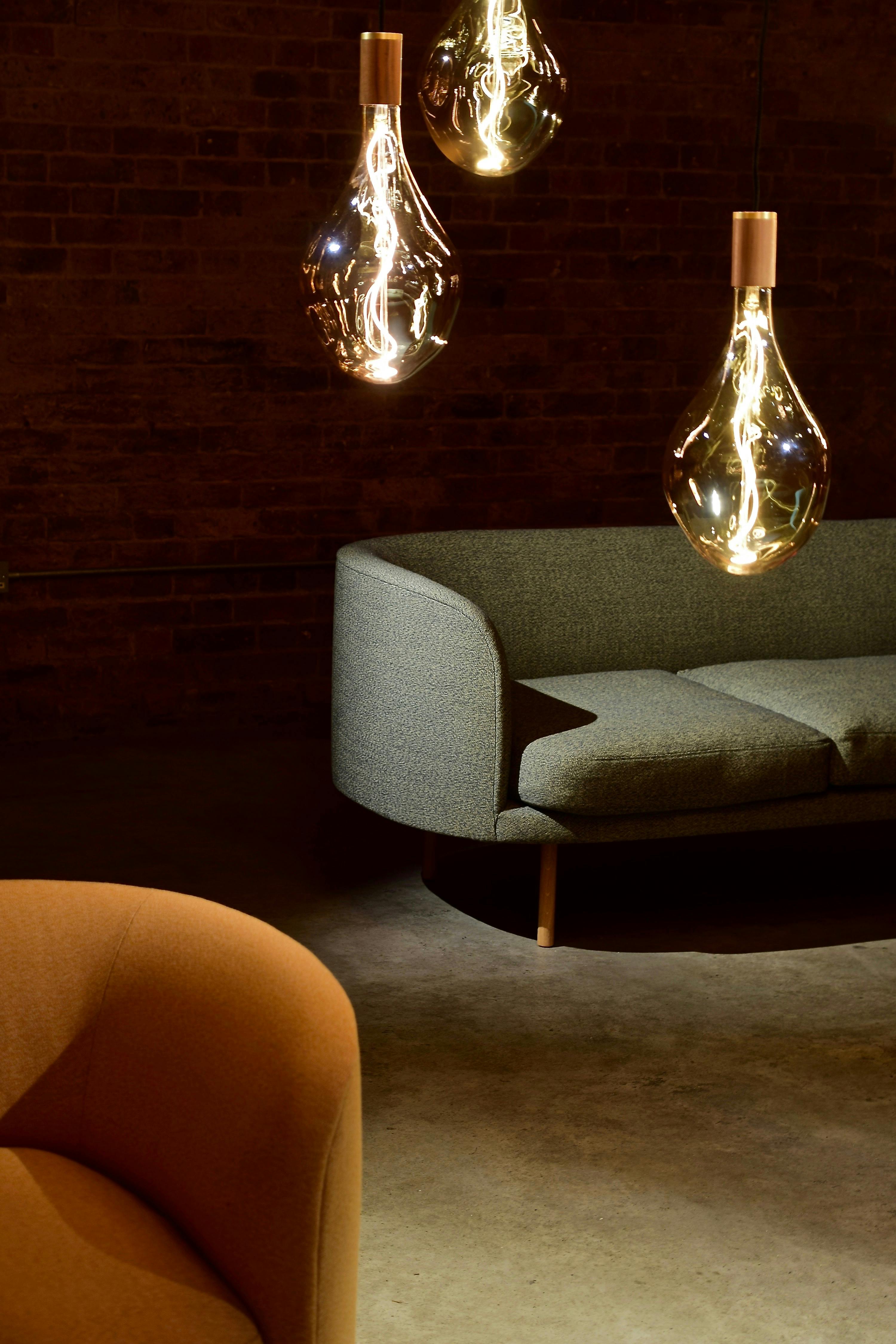 Picture of a room with a couch, a chair, and multiple hanging lightbulbs